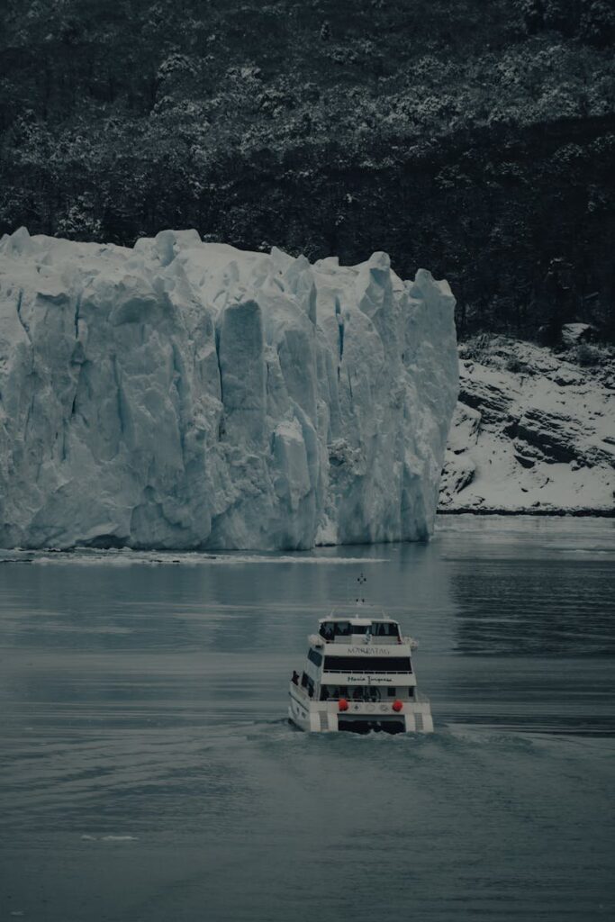 A stunning aerial view of a ship navigating icy waters near a massive glacier.