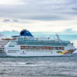 A majestic cruise ship sails near Puerto Plata, Dominican Republic, under a vibrant sky.