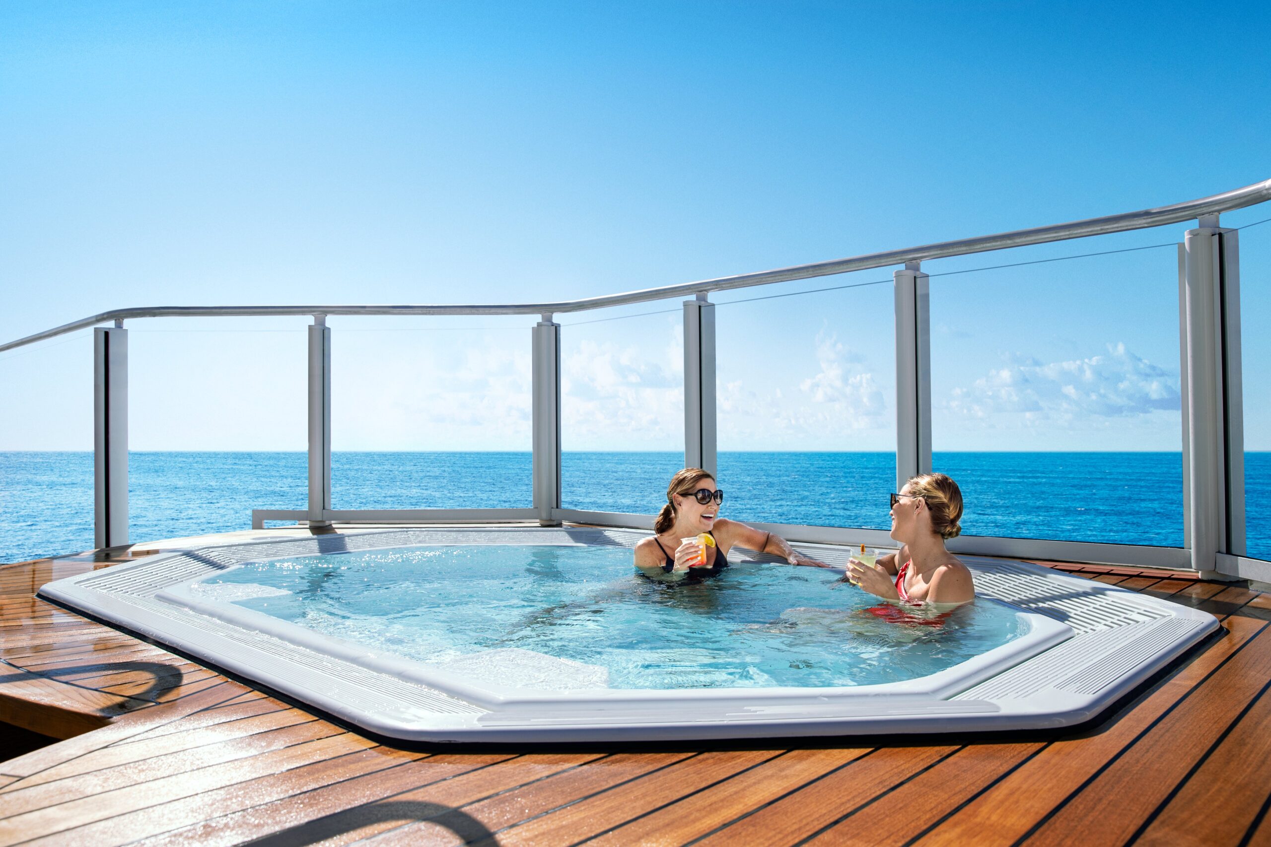 Two women enjoying a hot tub with ocean view.