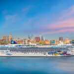 Cruise ship sailing near city skyline at sunset